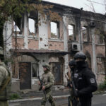 
              Ukrainian servicemen walk past heavily damaged building in the recaptured area in Izium, Ukraine, Wednesday, Sept. 14, 2022. (AP Photo/Leo Correa)
            