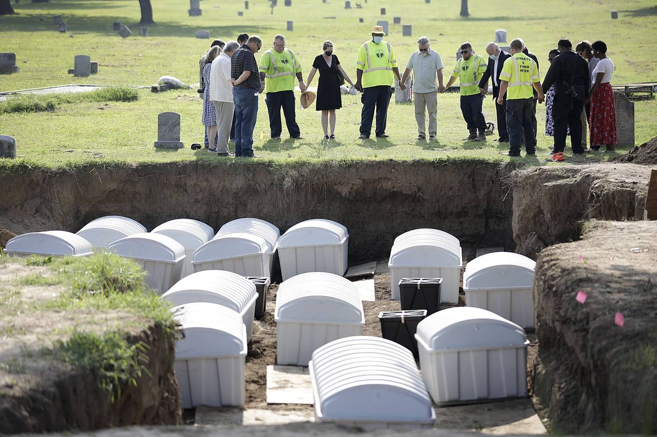 FILE - A group prays during a small ceremony as remains from a mass grave are re-interred at Oaklaw...