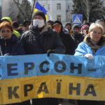 
              FILE - People hold a Ukrainian flag with a sign that reads: "Kherson is Ukraine", during a rally against the Russian occupation in Kherson, Ukraine, Sunday, March 20, 2022. Voting began Friday in four Moscow-held regions of Ukraine on referendums to become part of Russia. (AP Photo/Olexandr Chornyi, File)
            