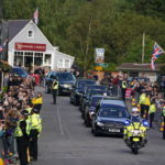 
              Members of the public line the streets in Ballater, Scotland, as the hearse carrying the coffin of Queen Elizabeth II passes through as it makes its journey to Edinburgh from Balmoral in Scotland, Sunday, Sept. 11, 2022. The Queen's coffin will be transported Sunday on a journey from Balmoral to the Palace of Holyroodhouse in Edinburgh, where it will lie at rest before being moved to London later in the week. (Andrew Milligan/PA via AP)
            