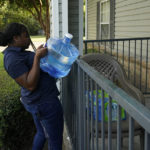 
              Mississippi Students Water Crisis Advocacy Team member Jordyn Jackson, uses her muscles to lift a container of water over the apartment terrace barrier in Jackson, Miss., as she and team members rush through their own delivery schedule, Sept. 8, 2022. A boil-water advisory has been lifted for Mississippi's capital, and the state will stop handing out free bottled water on Saturday. But the crisis isn't over. Water pressure still hasn't been fully restored in Jackson, and some residents say their tap water still comes out looking dirty and smelling like sewage. (AP Photo/Rogelio V. Solis)
            