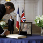 
              French President Emmanuel Macron signs a condolence book, following the passing of Britain's Queen Elizabeth, at the British Embassy in Paris, France, Friday, Sept. 9, 2022. Britain's longest-reigning monarch and a rock of stability across much of a turbulent century, died Thursday after 70 years on the throne. She was 96. (Christian Hartmann/Pool via AP)
            