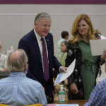 
              Republican gubernatorial candidate businessman Chris Doughty, top left, and his wife Leslie, top right, receive ballots from election workers before voting, Tuesday, Sept. 6, 2022, in Wrentham, Mass., in the state's primary election. Doughty, a political newcomer, is going up against Republican Geoff Diehl who has former President Donald Trump's endorsement. (AP Photo/Steven Senne)
            