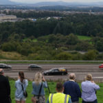 
              People watch the hearse carrying the coffin of Queen Elizabeth II, draped with the Royal Standard of Scotland, after it crossed Friarton Bridge as it continues its journey to Edinburgh from Balmoral, in Perth, Scotland, Sunday Sept. 11, 2022.   Queen Elizabeth II, Britain's longest-reigning monarch and a rock of stability across much of a turbulent century, died Thursday Sept. 8, 2022, after 70 years on the throne. She was 96. (Andrew Milligan/PA via AP)
            