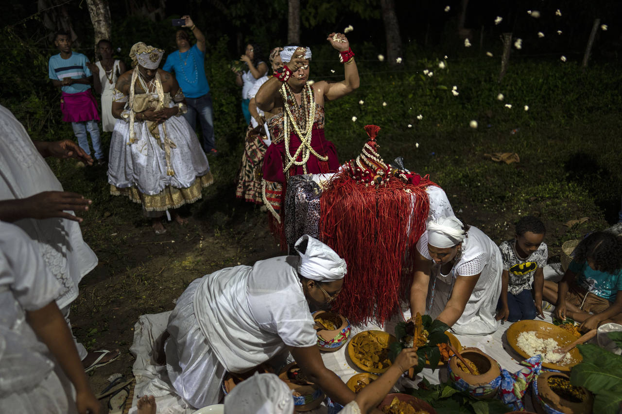 Thiago Viana, also known as Father Thiago of Oxum, tosses out pop corn during a ritual honoring Oba...