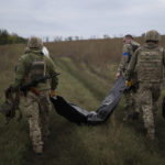 
              Ukrainian servicemen carry a bag containing the body of a Ukrainian soldier, center, as one of them, right, carries the remains of a body of a Russian soldier in a retaken area near the border with Russia in Kharkiv region, Ukraine, Saturday, Sept. 17, 2022. (AP Photo/Leo Correa)
            