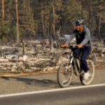
              A bicyclist passes Wakefield Ave. homes destroyed by the Mill Fire on Saturday, Sept. 3, 2022, in Weed, Calif. (AP Photo/Noah Berger)
            