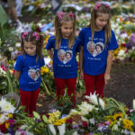 
              Sisters Arabella, 4, Elithia, 8 and Maisie, 9, from left, stand next to flowers and messages placed for Queen Elizabeth II at Green Park memorial next to Buckingham Palace in London, Monday, Sept. 12, 2022. Queen Elizabeth II, Britain's longest-reigning monarch and a rock of stability across much of a turbulent century, died Thursday Sept. 8, 2022, after 70 years on the throne. She was 96. (AP Photo/Emilio Morenatti)
            
