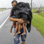
              A man carries two children in the rain in search of shelter after Hurricane Ian flooded their home in Pinar del Rio, Cuba, Tuesday, Sept. 27, 2022. Ian made landfall at 4:30 a.m. EDT Tuesday in Cuba’s Pinar del Rio province, where officials set up shelters, evacuated people, rushed in emergency personnel and took steps to protect crops in the nation’s main tobacco-growing region. (AP Photo/Ramon Espinosa)
            