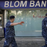 
              Lebanese policemen pass next to a bank that was attacked by depositors, in Beirut, Lebanon, Wednesday, Sept. 14, 2022. An armed woman and a dozen activists broke into a Beirut bank branch on Wednesday, taking over $13,000 from what she says were from her trapped savings. Lebanon's cash-strapped banks since 2019 have imposed strict limits on withdrawals of foreign currency, tying up the savings of millions of people. (AP Photo/Hussein Malla)
            