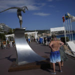 
              A couple stops along Nice's Promenade des Anglais to read the victims' names on "L'Ange de la Baie" statue created by Jean-Marie Fondacaro, to commemorate the 2016 terror attack, in Nice, South of France, Sunday, Sept. 4, 2022. Eight suspects will face trial in a Paris Court on Monday, in connection with the 2016 Bastille Day truck attack in Nice that left 86 people dead. (AP Photo/Daniel Cole)
            