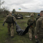 
              Ukrainian national guard servicemen carry a bag containing the body of a Ukrainian soldier in an area near the border with Russia, in Kharkiv region, Ukraine, Monday, Sept. 19, 2022. In this operation seven bodies of Ukrainian soldiers were recovered from what was the battlefield in recent months. (AP Photo/Leo Correa)
            
