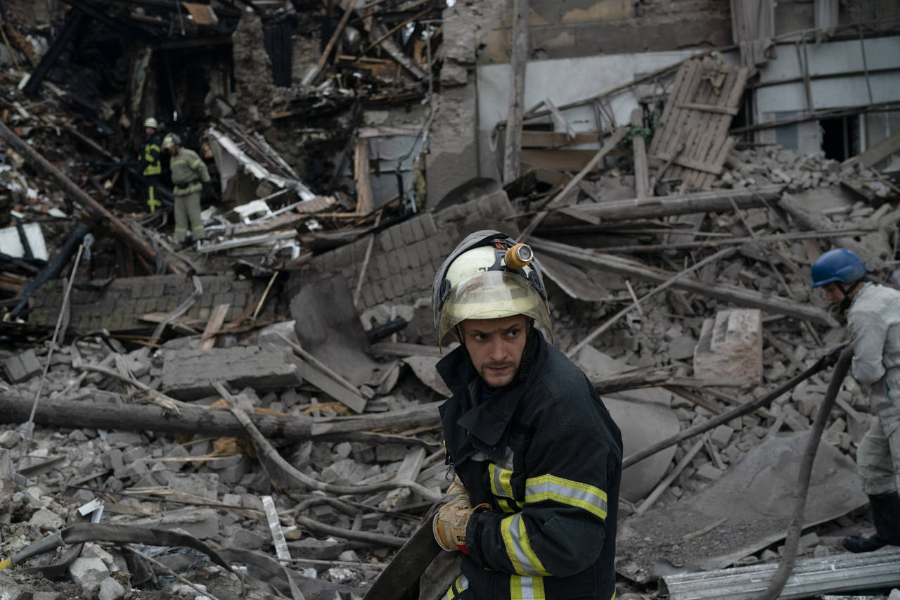 A firefighter works after a Russian attack that heavily damaged a building in Sloviansk, Ukraine, T...