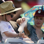 
              A woman hands a boy a frozen water bottle during the second inning of a baseball game between the Detroit Tigers and the Los Angeles Angels in Anaheim, Calif., Wednesday, Sept. 7, 2022. (AP Photo/Ashley Landis)
            