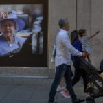 
              A man begs for alms next to a portrait of Queen Elizabeth II in central London, Tuesday, Sept. 13, 2022. Queen Elizabeth II, Britain's longest-reigning monarch and a rock of stability across much of a turbulent century, died Thursday Sept. 8, 2022, after 70 years on the throne. She was 96. (AP Photo/Emilio Morenatti)
            