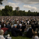 
              People sitting in Hyde Park, London, Wednesday, Sept. 14, 2022 watch screens broadcasting the procession of the coffin of Queen Elizabeth II from Buckingham Palace to Westminster Hall. The Queen will lie in state in Westminster Hall for four full days before her funeral on Monday Sept. 19. (AP Photo/Andreea Alexandru)
            