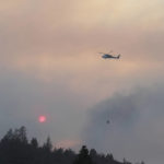 
              A helicopter carries water over a ridge to douse flames from a wildfire called the Mill Fire in the Lake Shastina Subdivision, northwest of Weed, Calif., Friday, Sept. 2, 2022. (Hung T. Vu/The Record Searchlight via AP)
            