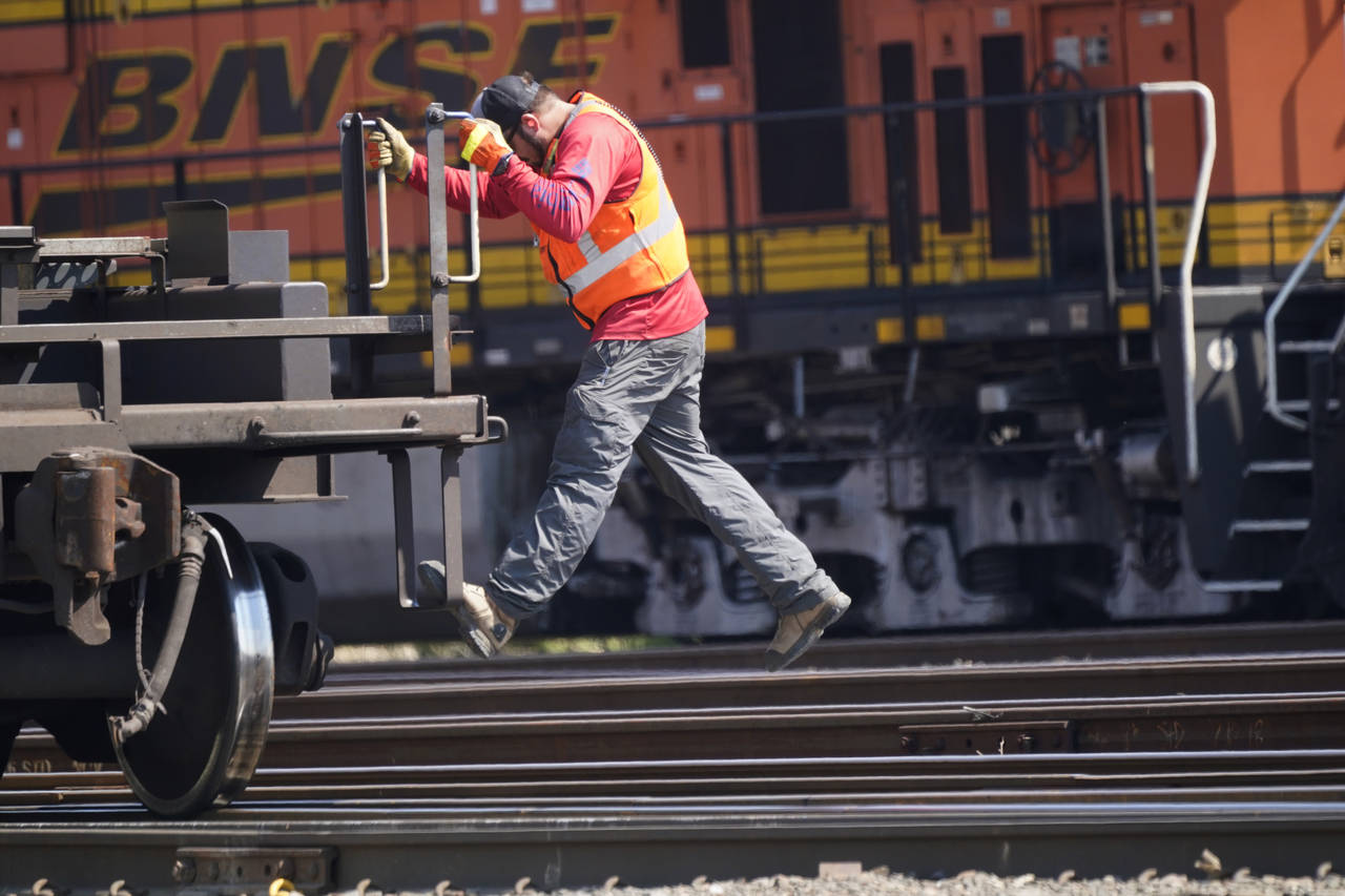 A worker rides a rail car at a BNSF rail crossing in Saginaw, Texas, Wednesday, Sept. 14, 2022. Bus...