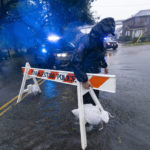 
              A Charleston police officer moves a barricade to block a flooded street as the effects from Hurricane Ian are felt, Friday, Sept. 30, 2022, in Charleston, S.C. (AP Photo/Alex Brandon)
            