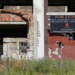 
              FILE - A lease sign hangs on the exterior of the Packard Plant on Detroit's east side on June 30, 2022. Demolition of the long-vacant Packard auto plant in Detroit started Thursday, Sept. 29, as crews began tearing apart an already crumbling exterior wall of the massive structure. (AP Photo/Carlos Osorio, File)
            