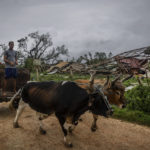 
              Men lead their ox cart past a tobacco warehouse smashed by Hurricane Ian in Pinar del Rio, Cuba, Tuesday, Sept. 27, 2022. Hurricane Ian tore into western Cuba as a major hurricane and left 1 million people without electricity, then churned on a collision course with Florida over warm Gulf waters amid expectations it would strengthen into a catastrophic Category 4 storm. (AP Photo/Ramon Espinosa)
            