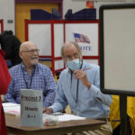 
              Election workers Joe Cormier, of South Dennis, Mass., center left, and Paul Freeman, of Wrentham, Mass., center right, assist voters in the Massachusetts' primary election at a voting station, Tuesday, Sept. 6, 2022, in Wrentham. (AP Photo/Steven Senne)
            