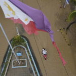 
              A tattered Philippine flag is seen over a flooded road due to Typhoon Noru in San Miguel town, Bulacan province, Philippines, Monday, Sept. 26, 2022. Typhoon Noru blew out of the northern Philippines on Monday, leaving some people dead, causing floods and power outages and forcing officials to suspend classes and government work in the capital and outlying provinces. (AP Photo/Aaron Favila)
            