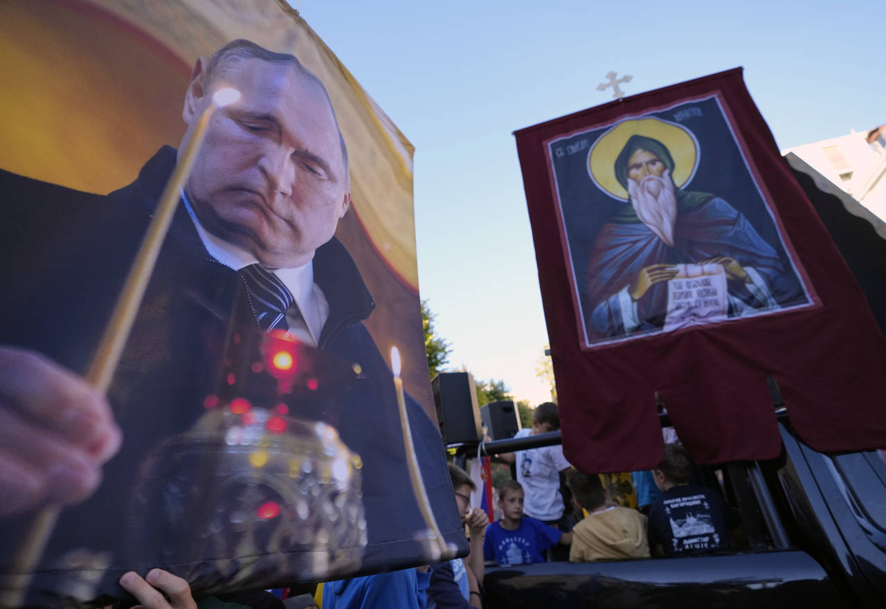 People hold icons and a picture of Russian President Vladimir Putin during a protest against the in...