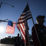 
              Dan Koster, with the Colorado Patriot Guard Riders, carries an American flag before lining up with other riders before the the funeral procession for fallen Arvada Police Officer Dillon Vakoff, Friday, Sept. 16, 2022, at Flatirons Community Church in Lafayette, Colo. Vakoff was fatally shot while trying to break up a large family disturbance earlier in the week, in Arvada. (Timothy Hurst/The Gazette via AP)
            