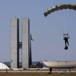
              An army paratrooper descends in front of the National Congress during a practice run in preparations for the country's bicentennial celebrations, in Brasilia, Brazil, Tuesday, Sept. 6, 2022. Brazil celebrates the bicentenary of its independence on Wednesday, Sept. 7. (AP Photo/Eraldo Peres)
            