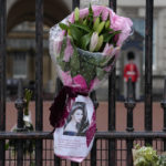 
              Flowers and a message are seen outside Buckingham Palace, rear, in London, Friday, Sept. 9, 2022. Queen Elizabeth II, Britain's longest-reigning monarch and a rock of stability across much of a turbulent century, died Thursday Sept. 8, 2022, after 70 years on the throne. She was 96. (AP Photo/Kirsty Wigglesworth)
            