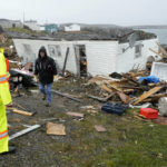 
              A search and rescue worker and a resident are seen on the lawn in front of a destroyed home in Port aux Basques, Newfoundland and Labrador, Monday, Sept.26, 2022. Across the Maritimes, eastern Quebec and in southwestern Newfoundland, the economic impact of hurricane Fiona's wrath is still being tallied.  (Frank Gunn/The Canadian Press via AP)
            