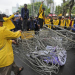 
              Student activists remove a police razor wire barricade during a rally against sharp increases in fuel prices, in Jakarta, Indonesia, Thursday, Sept. 8, 2022. Hundreds of students rallied in Indonesia's capital on Thursday to protest sharp increases in fuel prices by the government. (AP Photo/Achmad Ibrahim)
            