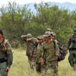 
              Migrants are led through desert at the base of the Baboquivari Mountains after being apprehended by U.S. Border Patrol agents, Thursday, Sept. 8, 2022, near Sasabe, Ariz. by U.S. Border Patrol agents. The desert region located in the Tucson sector just north of Mexico is one of the deadliest stretches along the international border with rugged desert mountains, uneven topography, washes and triple-digit temperatures in the summer months. Border Patrol agents performed 3,000 rescues in the sector in the past 12 months. (AP Photo/Matt York)
            