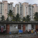 
              Children play in a poor neighborhood next to an upscale residential apartment building in Bengaluru, India, Wednesday, July 20, 2022. In this community, most people are from Assam state, many forced to migrate because of climate change and dreaming of a better future. (AP Photo/Aijaz Rahi)
            