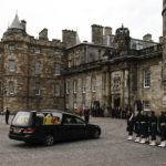 
              The hearse carrying the coffin of Queen Elizabeth II, draped with the Royal Standard of Scotland, completes its journey from Balmoral to the Palace of Holyroodhouse, where it will lie in rest for a day,  in Edinburgh, Sunday, Sept. 11, 2022. Queen Elizabeth II, Britain's longest-reigning monarch and a rock of stability across much of a turbulent century, died Thursday Sept. 8, 2022, after 70 years on the throne. She was 96.  (Aaron Chown/Pool Photo via AP)
            