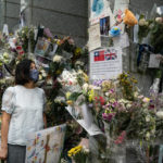 
              People look at flowers and messages placed for Queen Elizabeth II outside the British Consulate in Hong Kong, Friday, Sept. 16, 2022. In Britain, Thousands of mourners waited for hours Thursday in a line that stretched for almost 5 miles (8 kilometers) across London for the chance to spend a few minutes filing past Queen Elizabeth II's coffin while she lies in state. (AP Photo/Anthony Kwan)
            