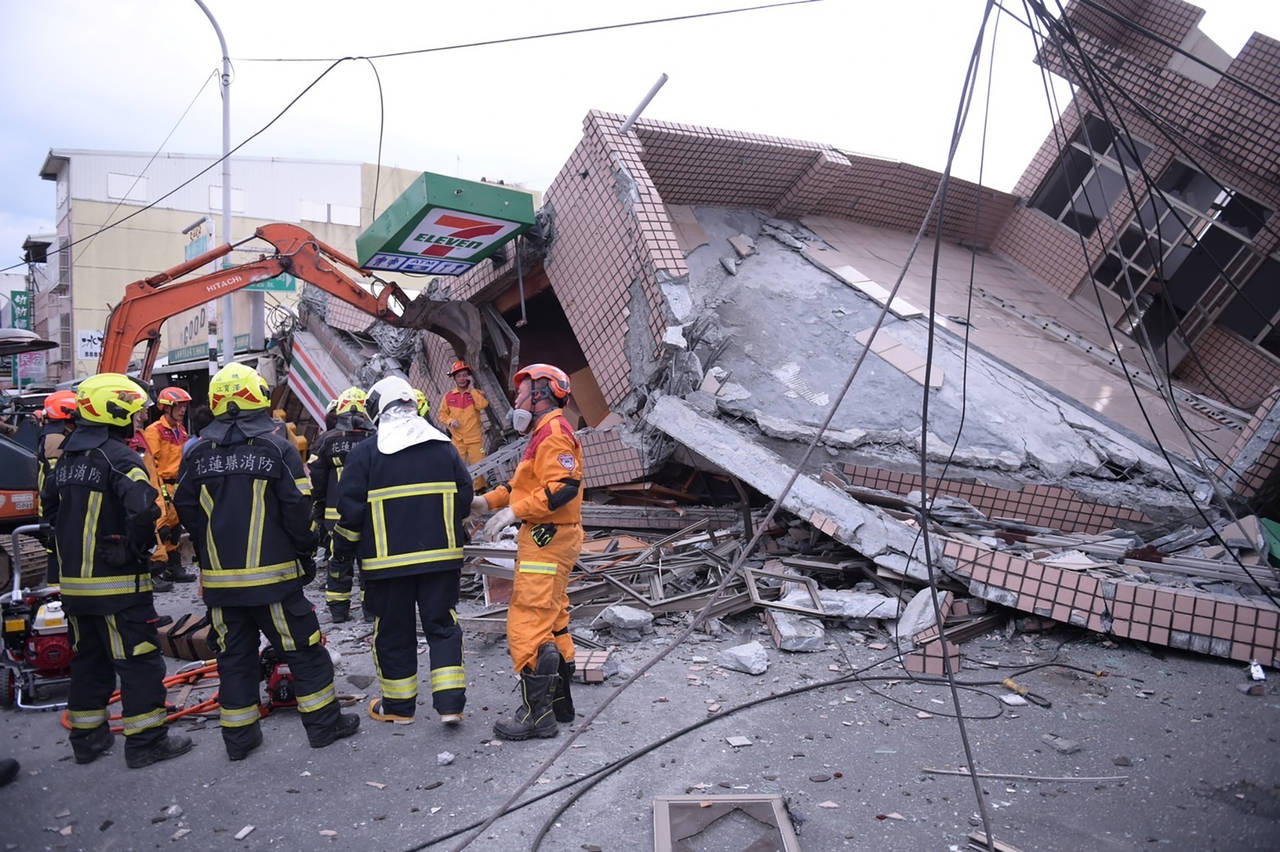 In this photo provided by Hualien City Government, firefighters are seen at a collapsed building du...