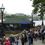 
              FILE - People walk walk past the Riverside Cafe as theyvqueue to pay their respect to the late Queen Elizabeth II during the lying-in state, in Westminster Hall in London, Thursday, Sept. 15, 2022. Hotels, restaurants and shops are packed as royal fans pour into the heart of London to experience the flag-lined roads, pomp-filled processions and brave a mileslong line for the once-in-a-lifetime chance to bid adieu to Queen Elizabeth II. (AP Photo/Petr David Josek, File)
            