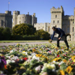 
              Workers from the Crown Estate move the floral tributes laid by members of the public outside Windsor Castle onto Cambridge Drive, near the Long Walk, Windsor, Sunday Sept. 18, 2022 ahead of the funeral of Queen Elizabeth II on Monday. (Victoria Jones/PA via AP)
            