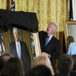 
              FILE - Former President Clinton, center, unveils his portrait as he and former first lady Hillary Clinton, right, participate in a ceremony for the unveiling of the Clinton portraits, June 14, 2004, in the East Room of the White House in Washington. (AP Photo/Ron Edmonds, File)
            