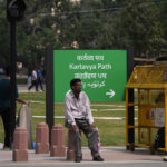 
              A man rests on a newly constructed pillar in front of a road signage which is changed from Rajpath  to Kartavya Path, in New Delhi, Sunday, Sept. 11, 2022. On Thursday, Sept. 8, 2022, India’s Prime Minister Narendra Modi urged the country to shed its colonial ties in a ceremony to rename Rajpath, a boulevard that was once called Kingsway after King George V, Modi called it a "symbol of slavery" under the British Raj. (AP Photo/Manish Swarup)
            