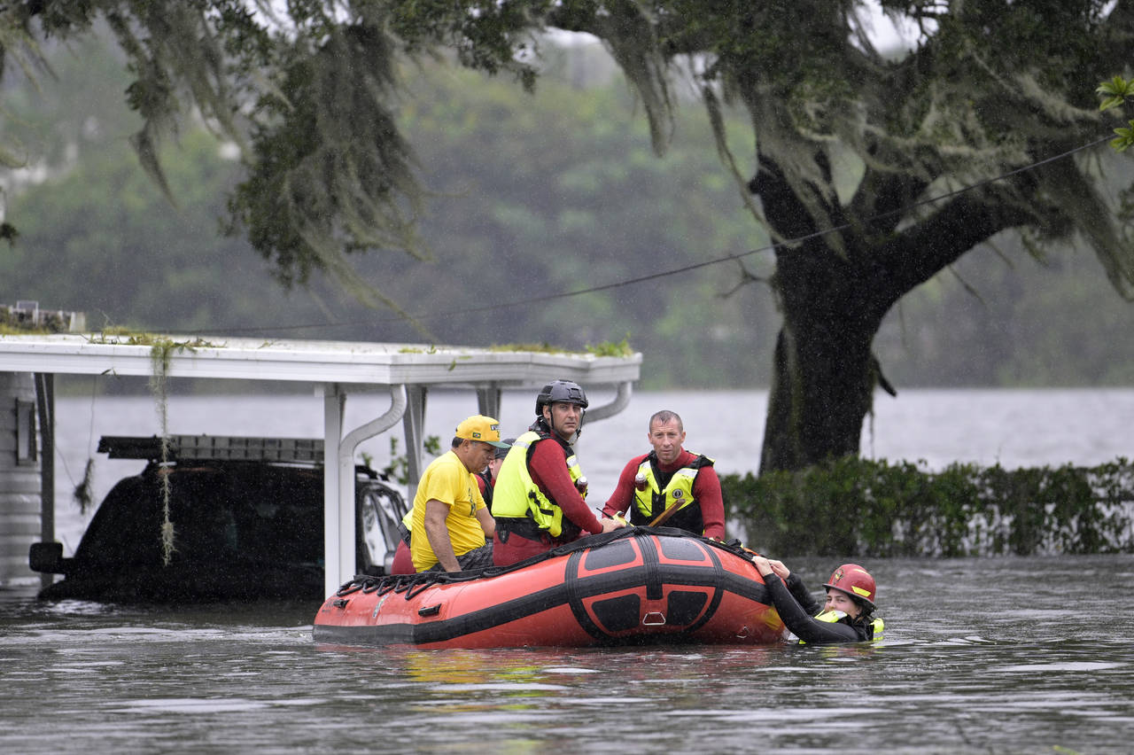 First responders with Orange County Fire Rescue use an inflatable boat to rescue a resident from a ...