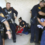 
              Police tend to a man after he shoved his first through a window in an effort to gain entry to Thomas Jefferson High School in San Antonio,  as chaos ensues outside the school after it went into lockdown on Tuesday, Sept. 20, 2022. Alarmed parents laid siege to the Texas high school Tuesday after a classroom shooting report that ultimately proved to be false. (Kin Man Hui/The San Antonio Express-News via AP)
            