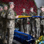 
              Servicemen pay last respect at the coffin of Olga Simonova, 34, a Russian woman who was killed in the Donetsk region while fighting on Ukraine's side in the war with her native country, in a crematorium in Kyiv, Ukraine, Friday, Sept. 16, 2022. (AP Photo/Roman Hrytsyna)
            