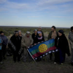 
              Indigenous Mapuche pose for photos with their Indigenous flag at the base of the Andean Condor Conservation Program, the day before freeing two Andean condors that had been born in captivity almost three years prior in Sierra Paileman in the Rio Negro province of Argentina, Thursday, Oct. 13, 2022. For 30 years the Andean Condor Conservation Program has hatched chicks in captivity, rehabilitated others and freed them across South America. (AP Photo/Natacha Pisarenko)
            