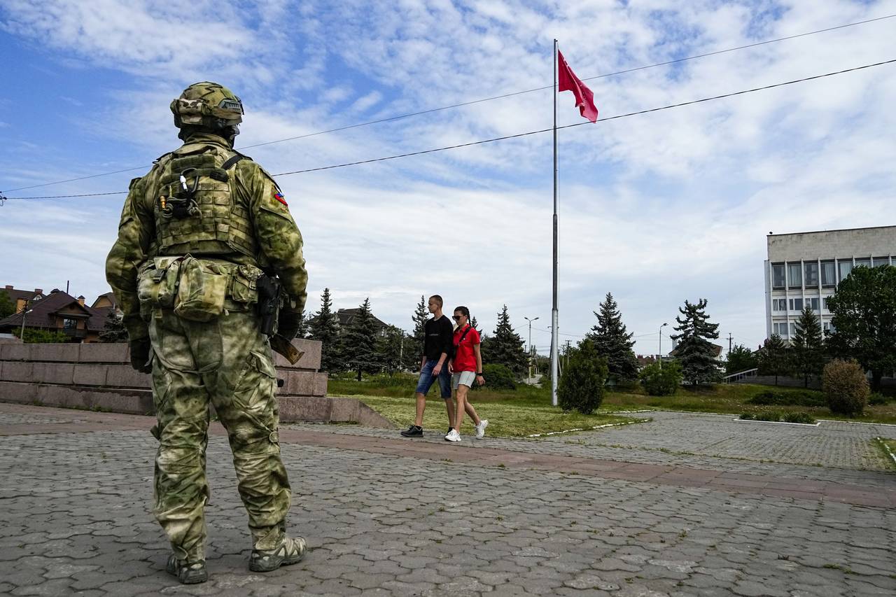 FILE - A young couple walks past a Russian soldier guarding an area at the Alley of Glory exploits ...
