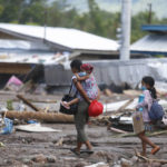 
              Residents walk beside remains of damaged homes at Maguindanao's Datu Odin Sinsuat town, southern Philippines on Sunday Oct. 30, 2022. Victims of a huge mudslide set off by Tropical Storm Nalgae in a coastal Philippine village that had once been devastated by a killer tsunami mistakenly thought a tidal wave was coming and ran to higher ground toward a mountain and were buried alive, an official said Sunday. (AP Photo)
            