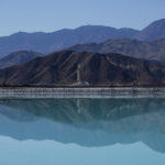 
              Mountains and a liming facility are reflected in a brine evaporation pond at Albemarle Corp.'s Silver Peak lithium facility, Thursday, Oct. 6, 2022, in Silver Peak, Nev. The ponds use evaporation to help separate lithium from brine pumped from underground. The Biden administration on Wednesday, Oct. 19, awarded $2.8 billion in grants to build and expand domestic manufacturing of batteries for electric vehicles in 12 states. A total of 20 companies, including Albemarle Corp., will receive grants for projects to extract and process lithium, graphite and other battery materials, manufacture components and strengthen U.S. supply of critical minerals, officials said. (AP Photo/John Locher)
            