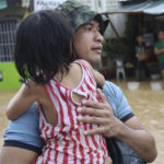 
              In this photo provided by the Philippine Coast Guard, a rescuer carries a child to safer grounds as floods rose due to Tropical Storm Nalgae at Parang, Maguindanao province, southern Philippines on Friday Oct. 28, 2022. (Philippine Coast Guard via AP)
            